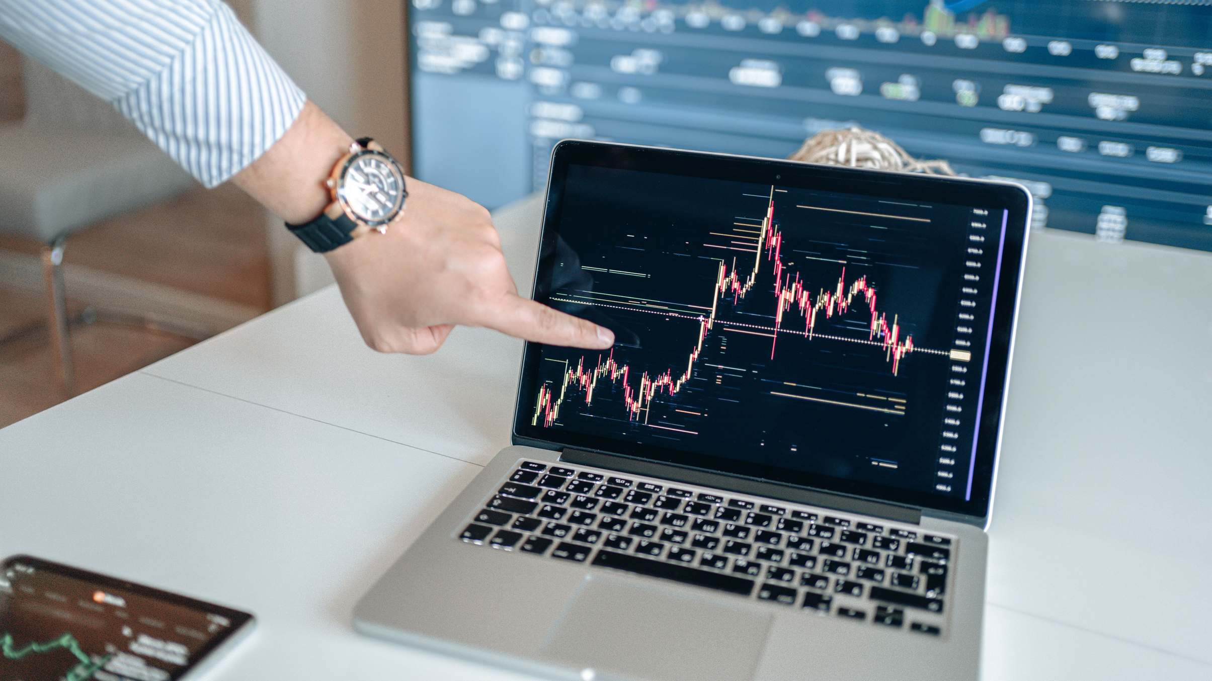 Hände an einer Tastatur, auf dem Bildschirm Finanzcharts und Datenanalysen